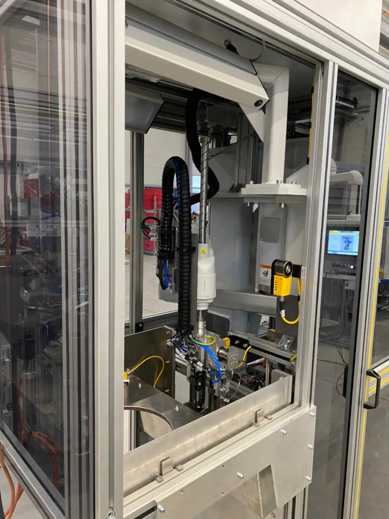 Innenansicht der Automatisierungslösung von Ralf Lang Maschinenbau GmbH mit Scara-Roboter, Kameraprüfung und Schraubenbestückung für Getriebe- und Mechatronikbaugruppen.